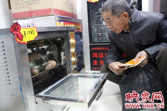 一名科技會(huì)員在看一臺自動(dòng)化烤紅薯機(jī)器 一名科技會(huì)員在看一臺自動(dòng)化烤紅薯機(jī)器