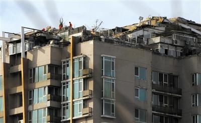 　　昨日，身穿橘黃色馬甲的工作人員在人濟(jì)山莊樓頂拆除違章建筑。新京報記者 吳江 攝