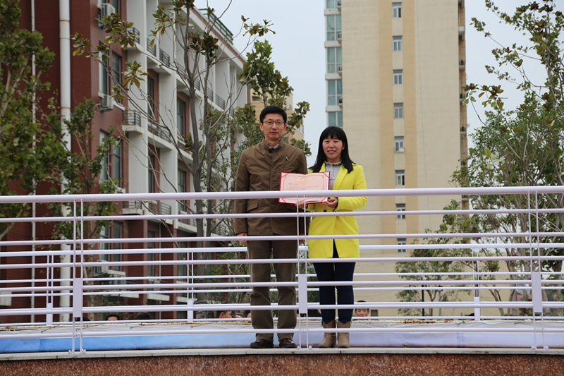 校長(zhǎng)董震（左一）為魏瑋老師頒發(fā)證書