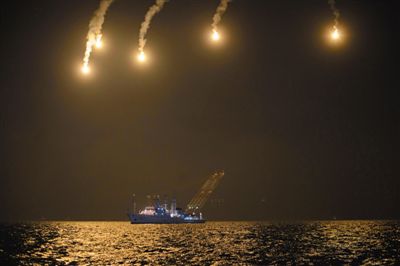 22日，搜救人員在照明彈的光亮下連夜搜救。