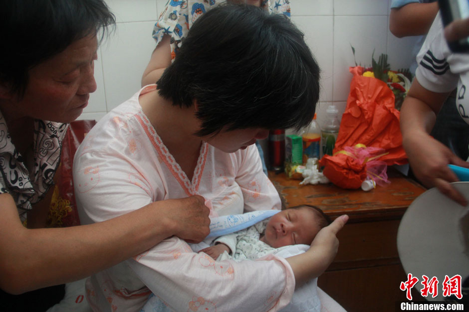 圖為久別重逢，獲救嬰兒母親悉心撫摸愛(ài)子。張一辰 攝