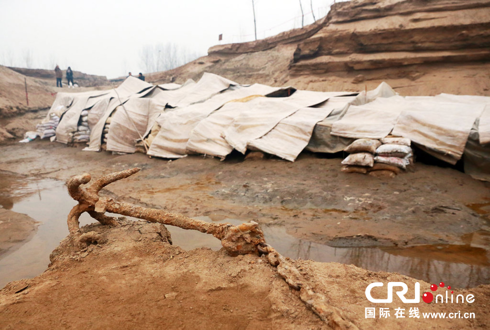 2014年1月6日，河南洛陽古沉船發(fā)掘現(xiàn)場，古沉船鐵錨從見天日，靜靜地躺在古船旁。