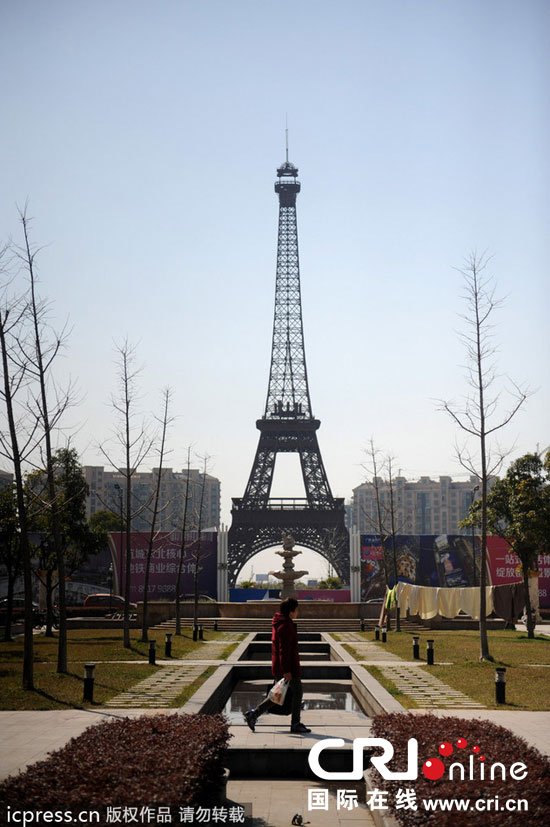 　2014年3月21日，杭州天都城，農(nóng)民在山寨埃菲爾鐵塔下耕作。圖片來源：東方IC