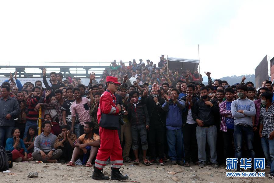 圍觀的尼泊爾民眾在中國國際救援隊成功搜救出幸存者后向搜救隊員歡呼致意。