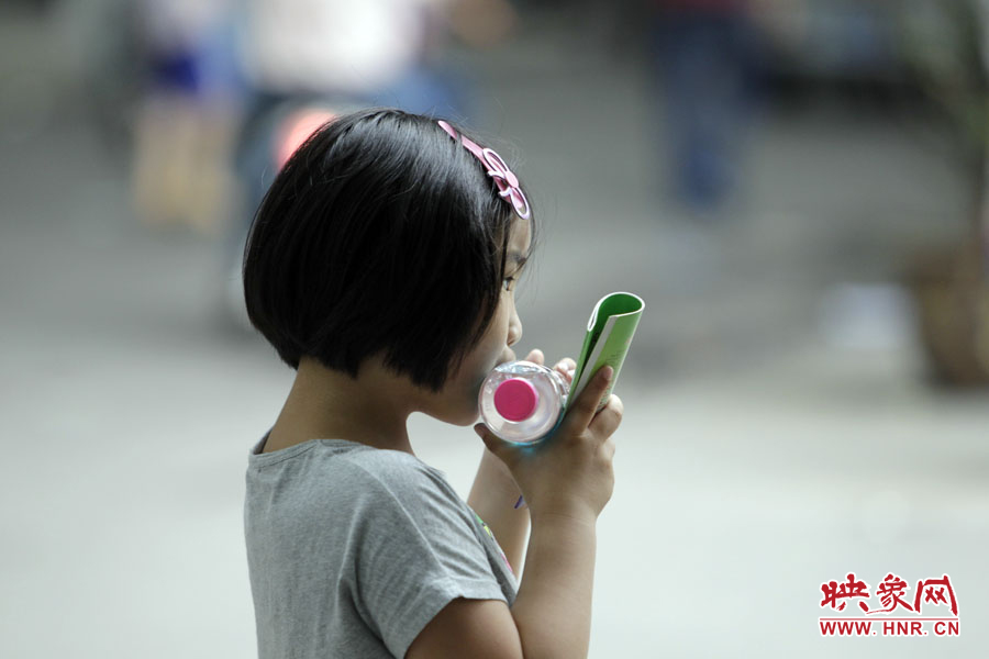 6月7日，鄭州回中考點(diǎn)，一名孩子拿著一瓶礦泉水，等待哥哥走出考場