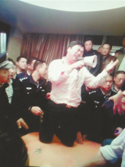 　4月19日，泰州市濱江工業(yè)園區(qū)管委會招待中心，一男子跪在酒桌上喊話求饒。李根 攝