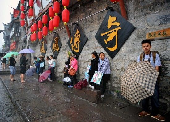 　4月29日上午11時20分，一些游客和古城當(dāng)?shù)氐木用穸阍谝粋€酒吧的屋檐下避雨。這些當(dāng)?shù)鼐用褚詾橛慰团恼罩\生，一場降雨讓他們的生意更加清淡。