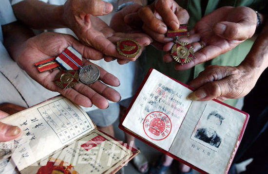 幾位志愿軍老兵展示自己的立功證、傷殘軍人證與勛章