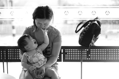 昨日，肯德基京廣中心店門(mén)口，姜女士提起跟養(yǎng)父母的關(guān)系時(shí)落淚，懷中9個(gè)月的女兒笑著跟她玩。新京報(bào)記者 薛珺 攝