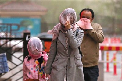 昨日下午，朝陽區(qū)豆各莊，行人將紗巾裹在頭上防沙塵。