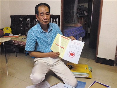 翻出一家網(wǎng)站贈(zèng)予的“中國好人”證書，區(qū)少坤單膝跪在地上，“你看，我是中國好人啊?！?范春旭 攝