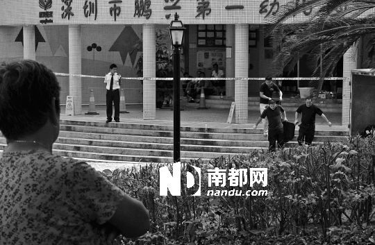 →7月19日，鵬興花園第一幼兒園門前，民警在現(xiàn)場進行完勘查取證后，園長和保安的尸體被運走。南都記者 徐文閣 攝