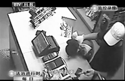 戴帽男子一手掐住加油站營業(yè)員，一手持發(fā)令槍指向另一營業(yè)員，要求“把錢給我裝起來”。