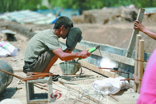 　正午陽光下，工地上的焊接工人還在認(rèn)真工作。
