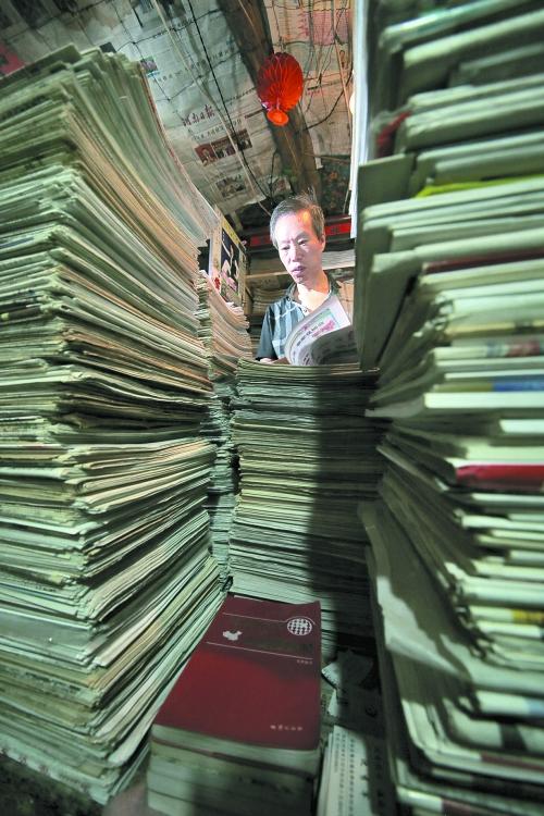 王曉民坐在寫字桌前，被報(bào)紙淹沒。