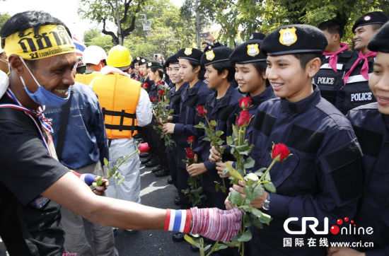 2013年12月03日,曼谷總理府與曼谷警署允許反政府示威民眾進(jìn)入,雙方進(jìn)入暫時(shí)“停戰(zhàn)”狀態(tài)迎接泰王生日。曼谷警察總署,女警們手持鮮花送給反政府示威民眾。圖片來源:Manish Swarup/東方IC