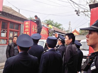 昨日下午,東城區(qū)工商、城管、公安等部門,對(duì)雍和宮附近的預(yù)測(cè)中心進(jìn)行清理整頓,站在車頂?shù)膬擅と苏鸪患摇邦A(yù)測(cè)中心”的招牌。因雍和宮、白云觀等文化景點(diǎn)外聚集大量算命先生,被媒體稱為“算命一條街”。本版攝影/新京報(bào)記者 李寧 攝