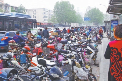 省人民醫(yī)院北門，路邊的公交站牌處停滿非機(jī)動車，上、下客只能在快車道上。