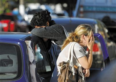 27日，遇難者親友在火災現(xiàn)場旁哭泣。