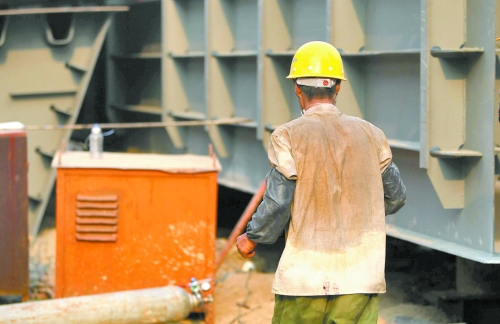 工地上，一建筑工人的衣服被汗水浸透。