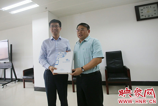 阿里云計算總裁胡曉明向河南省新聞出版廣電局局長朱夏炎遞交《中原云平臺交付手冊》。