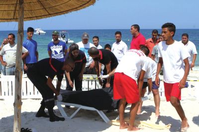 6月26日，在突尼斯蘇塞，救生員和醫(yī)務(wù)人員在發(fā)生襲擊事件的海灘運(yùn)送一名死者的遺體。新華社發(fā)