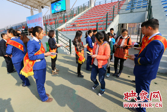 活動現(xiàn)場工作人員給同學(xué)們發(fā)放宣傳冊、環(huán)保袋。