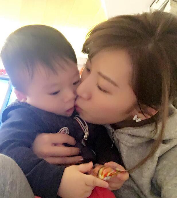 照片中李念狂吻兒子，小寶貝自顧自地玩著。