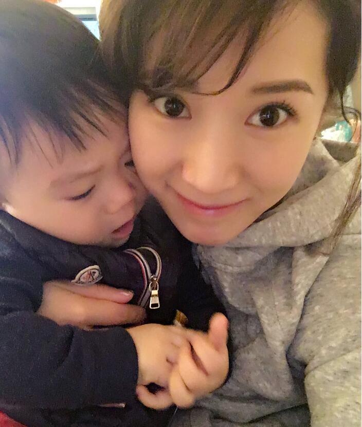 照片中李念狂吻兒子，小寶貝自顧自地玩著。