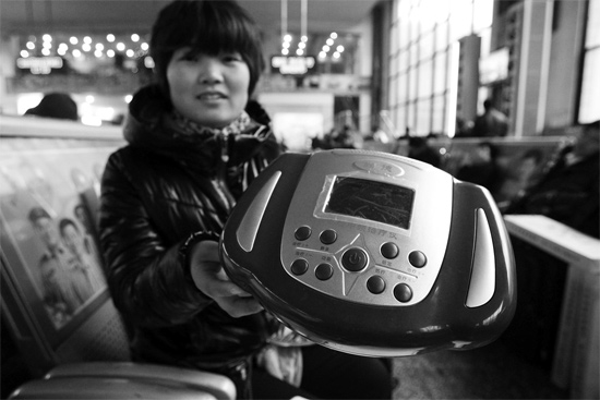 火車(chē)站候車(chē)室，李女士向記者展示她準(zhǔn)備孝敬父母的按摩儀