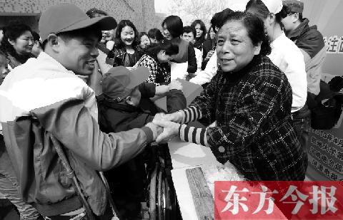 昨日，鄭大四附院的大樓前，“面人鄭”鄭玉芬（右）向前來捐款的殘疾人表示感謝