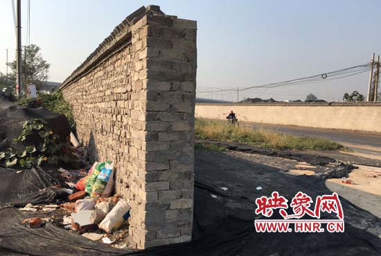 一墻之隔，一邊是道路，一邊是垃圾和荒草，市民質(zhì)疑其為遮羞墻。
