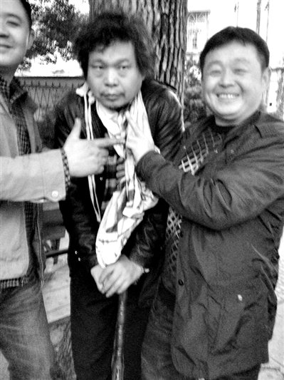 兩名接訪人員與患有癌癥的訪民段新德合影時(shí)，面帶笑容擺出勝利的手勢(shì)。