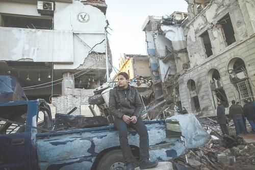 埃及曼蘇拉市警察局24日遭汽車炸彈襲擊，被疑是穆兄會(huì)的報(bào)復(fù)。圖為一名男子在被炸毀的警察局前。