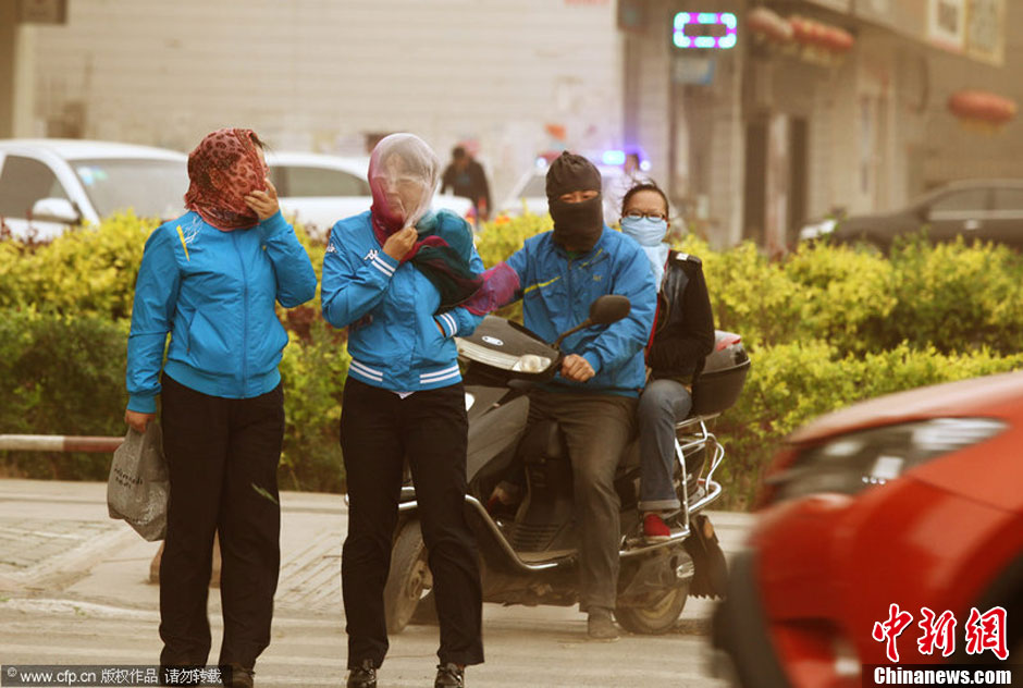 2014年04月23日，新疆維吾爾自治區(qū)吐魯番地區(qū)，市民戴著口罩行走在大風(fēng)沙塵中的吐魯番市街頭。