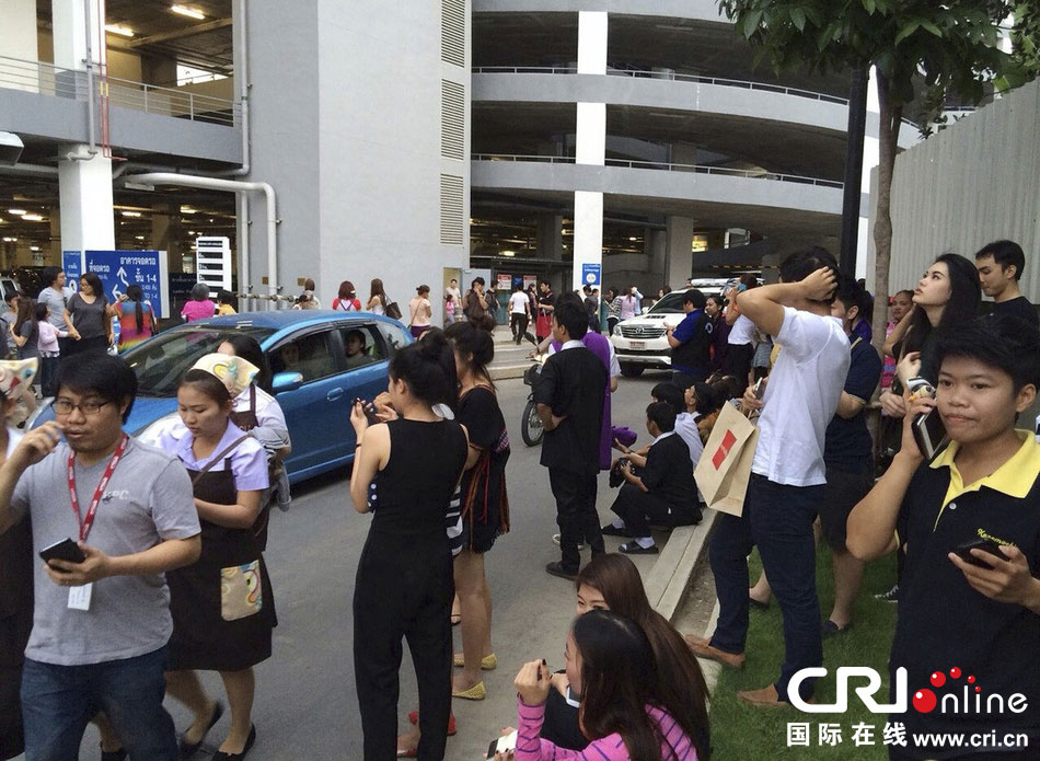 當?shù)貢r間2014年5月5日，泰國清萊，工人們站在一棟大樓外避難。