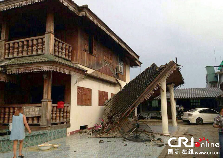 當?shù)貢r間2014年5月5日，泰國清萊，一名婦女看著受損的房屋。 圖片來源：東方IC