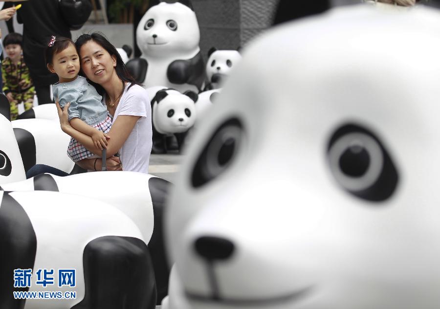 6月2日，一位家長帶著孩子在上海街頭和大熊貓模型合影。