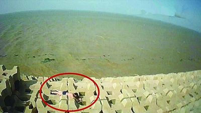 孫正龍游上岸，趴在海邊精疲力盡。