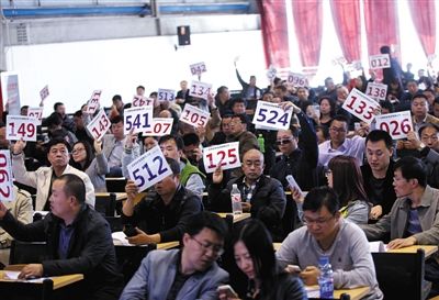 競(jìng)拍者正在練習(xí)舉牌動(dòng)作，以便拍賣(mài)時(shí)讓工作人員看清號(hào)牌。