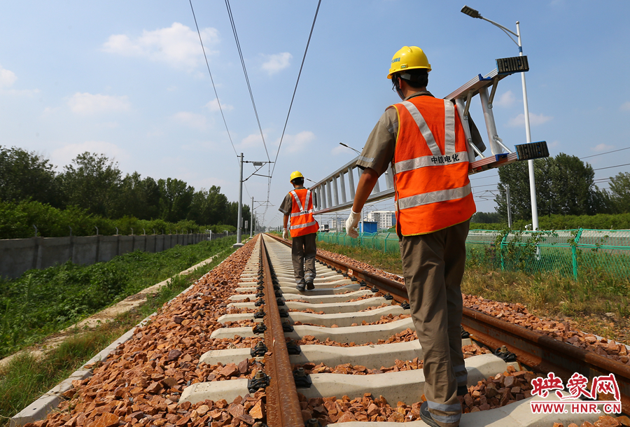 滾燙的鐵軌上，兩個(gè)扛著梯子的檢修員走向第四個(gè)檢修點(diǎn)