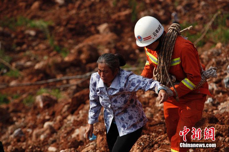 一位消防戰(zhàn)士將一位失去親人的老人扶離滑坡點。
