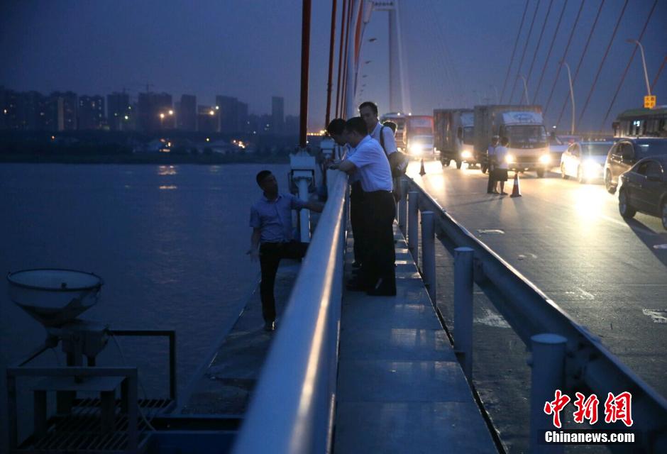 圖為武漢警方談判專家正在與翻爬至大橋外側(cè)護(hù)欄的劫持者談判。