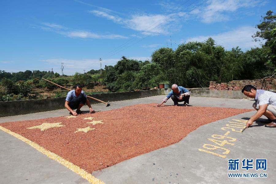 村民馬玉明（左一）用豐收的高粱和玉米在院壩里擺國旗為祖國慶生。