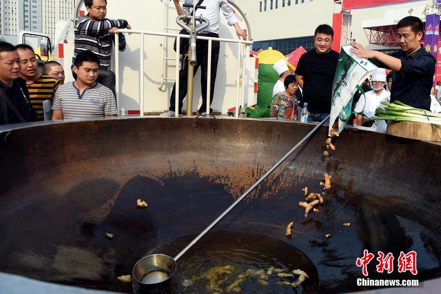 工作人員向大鍋內(nèi)加入油和姜等烹飪調(diào)料。 圖片來源：CFP視覺中國