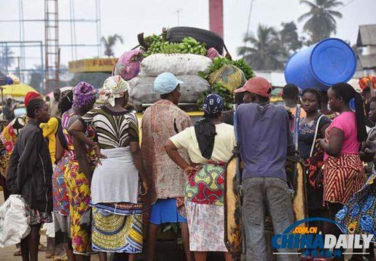 當(dāng)?shù)貢r(shí)間2014年8月14日，利比里亞蒙羅維亞，市場(chǎng)里的商人們圍著一輛汽車。