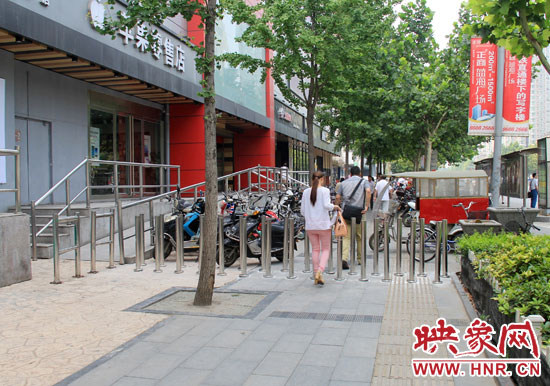 圖中道路左側的無障礙通道被鋼管隔離,右側的盲道也被侵占。