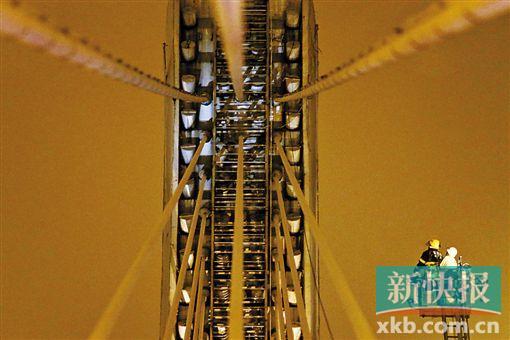 截至今日零時(shí)，男子仍未有下橋舉動(dòng)。圖為公安和消防人員乘消防云梯在高空上和男子交談。