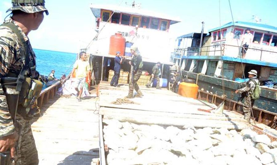 圖為菲律賓海軍持槍檢查中國(guó)漁民的照片。