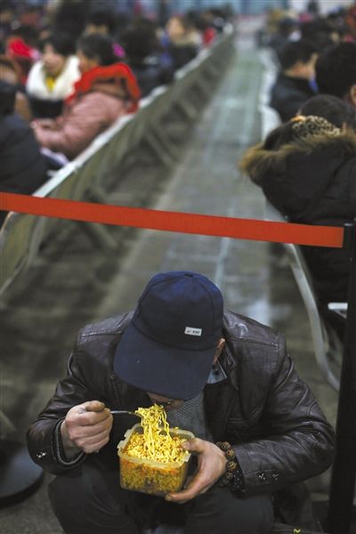 北京西站臨時(shí)候車廳，鄧軍吃著妻子泡好的方便面